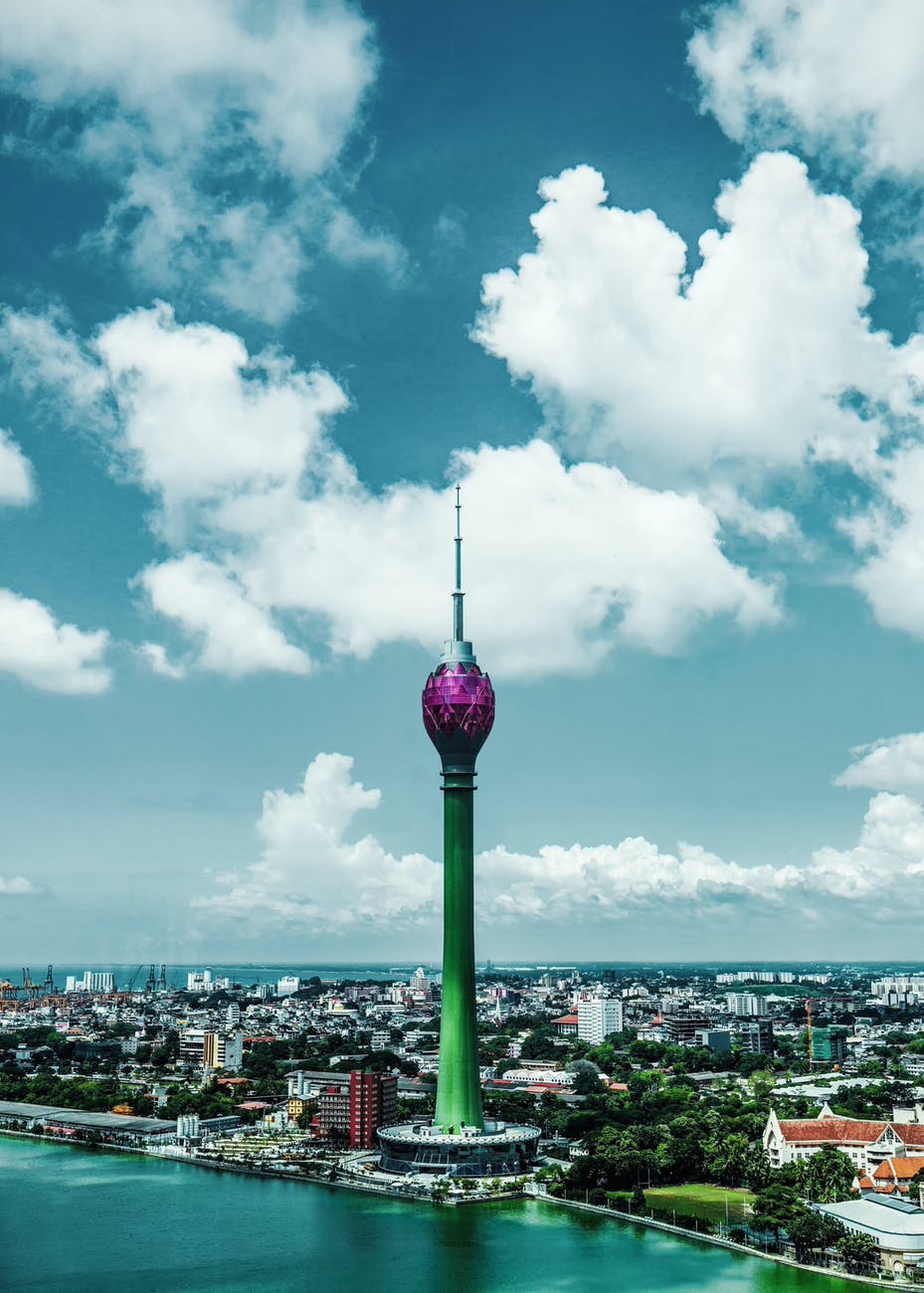 green and pink tower under blue sky and white clouds